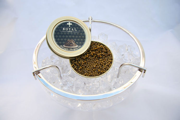 Geöffnete Dose Stör Kaviar der Sorte Royal Premium auf Eis in Kristall-Schale serviert.